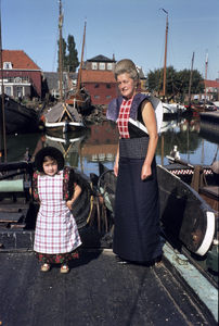 852319 Afbeelding van een vrouw en kind in klederdracht in de haven van Spakenburg.